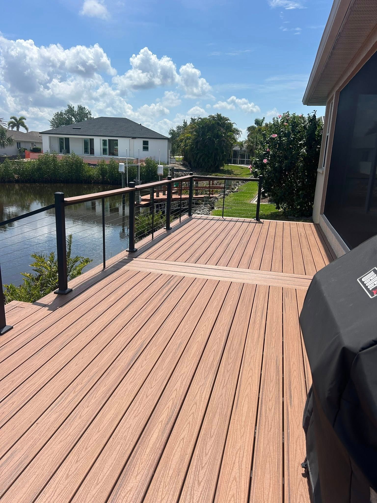 A wooden deck with a grill on it and a river in the background.