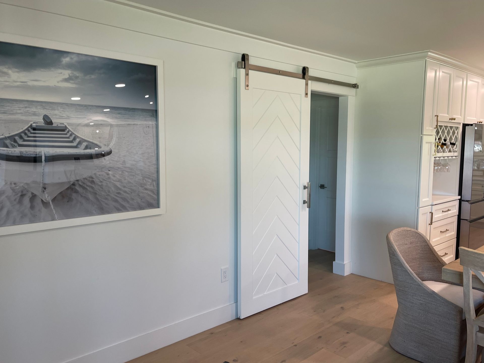 There is a picture of a boat on the wall above the sliding barn door.