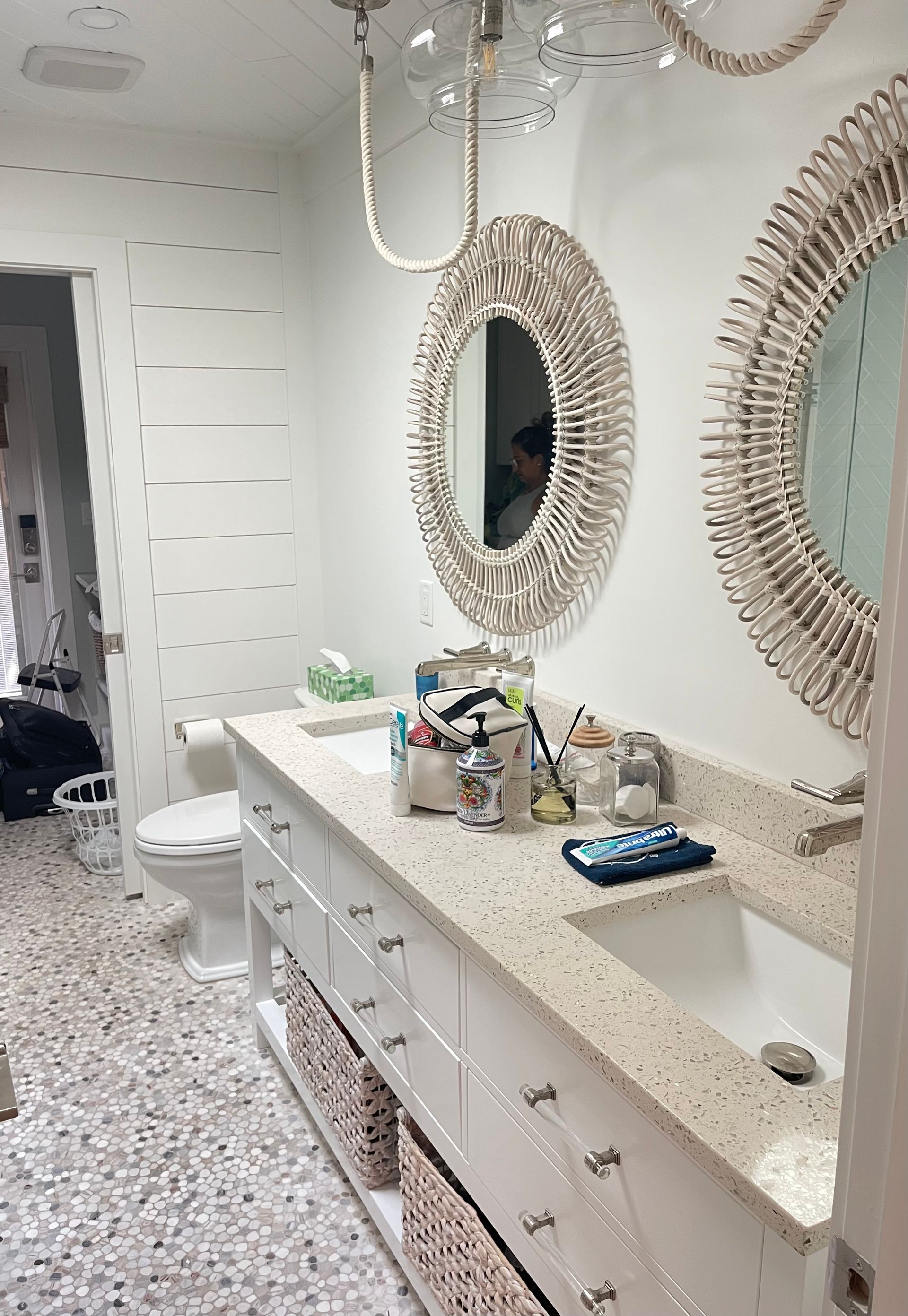 A bathroom with two sinks , two mirrors and a toilet.