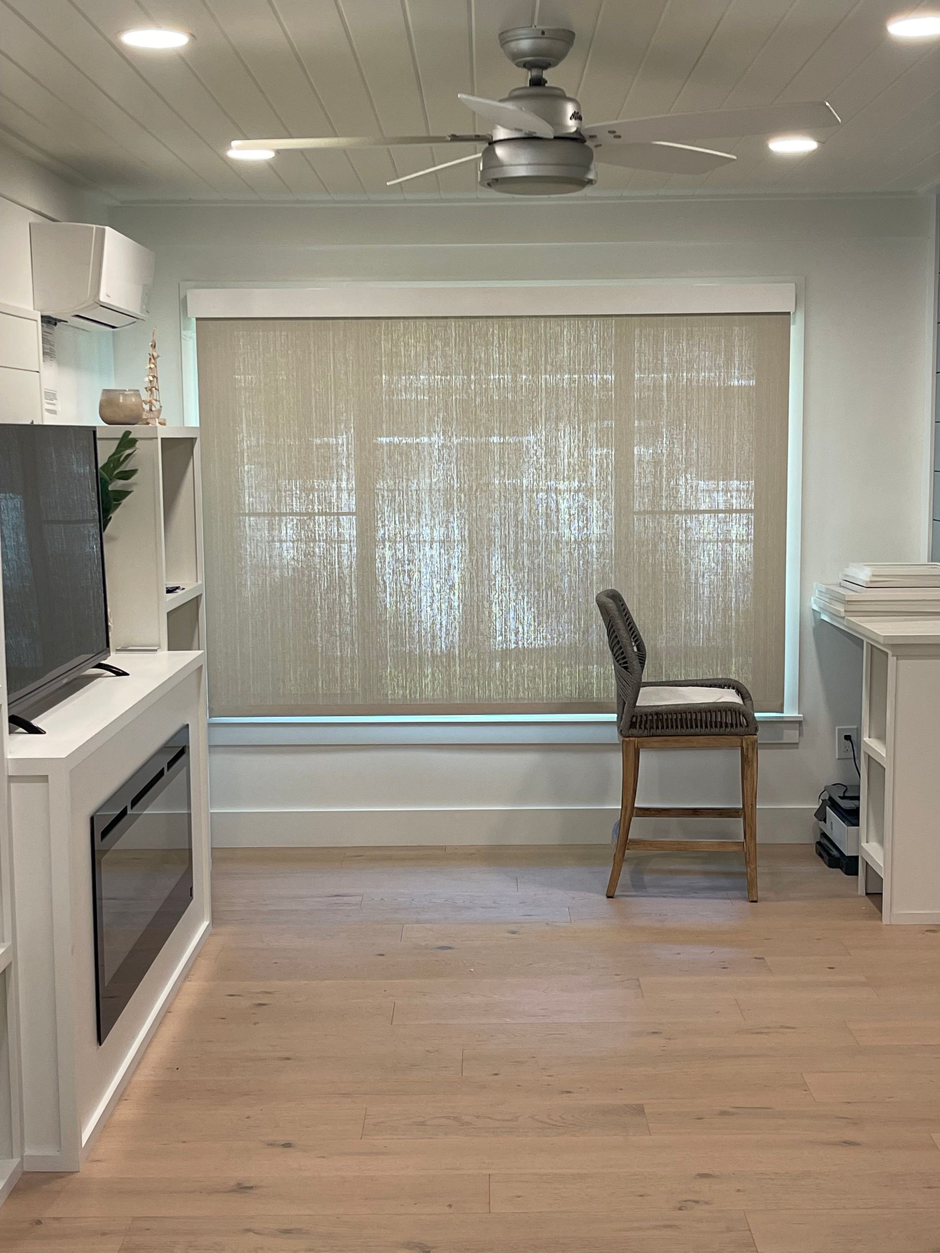 A living room with a fireplace , television , chair and ceiling fan.