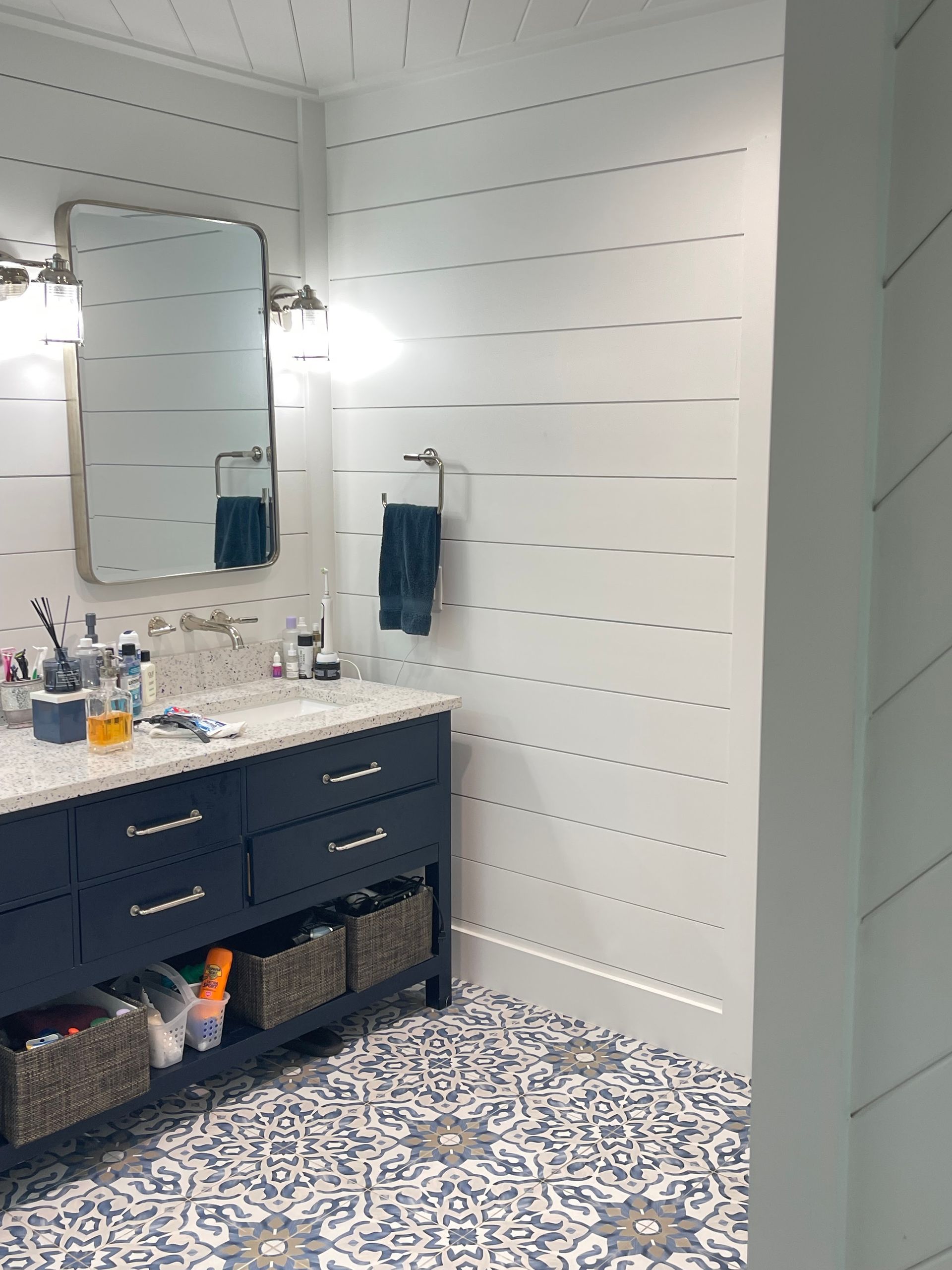 A bathroom with two sinks , a mirror , and baskets on the floor.