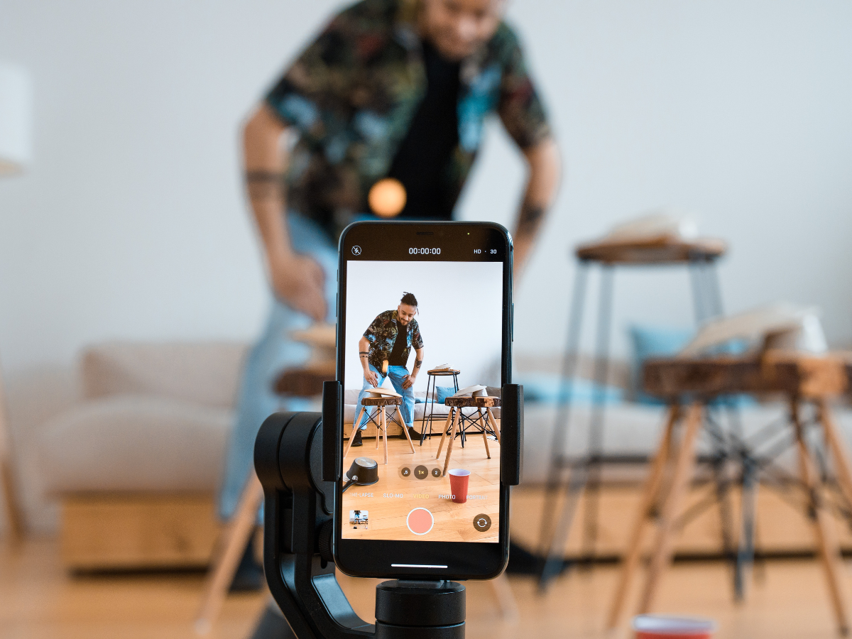 A man is standing in front of a cell phone on a tripod. A man is standing in front of a cell phone on a tripod.