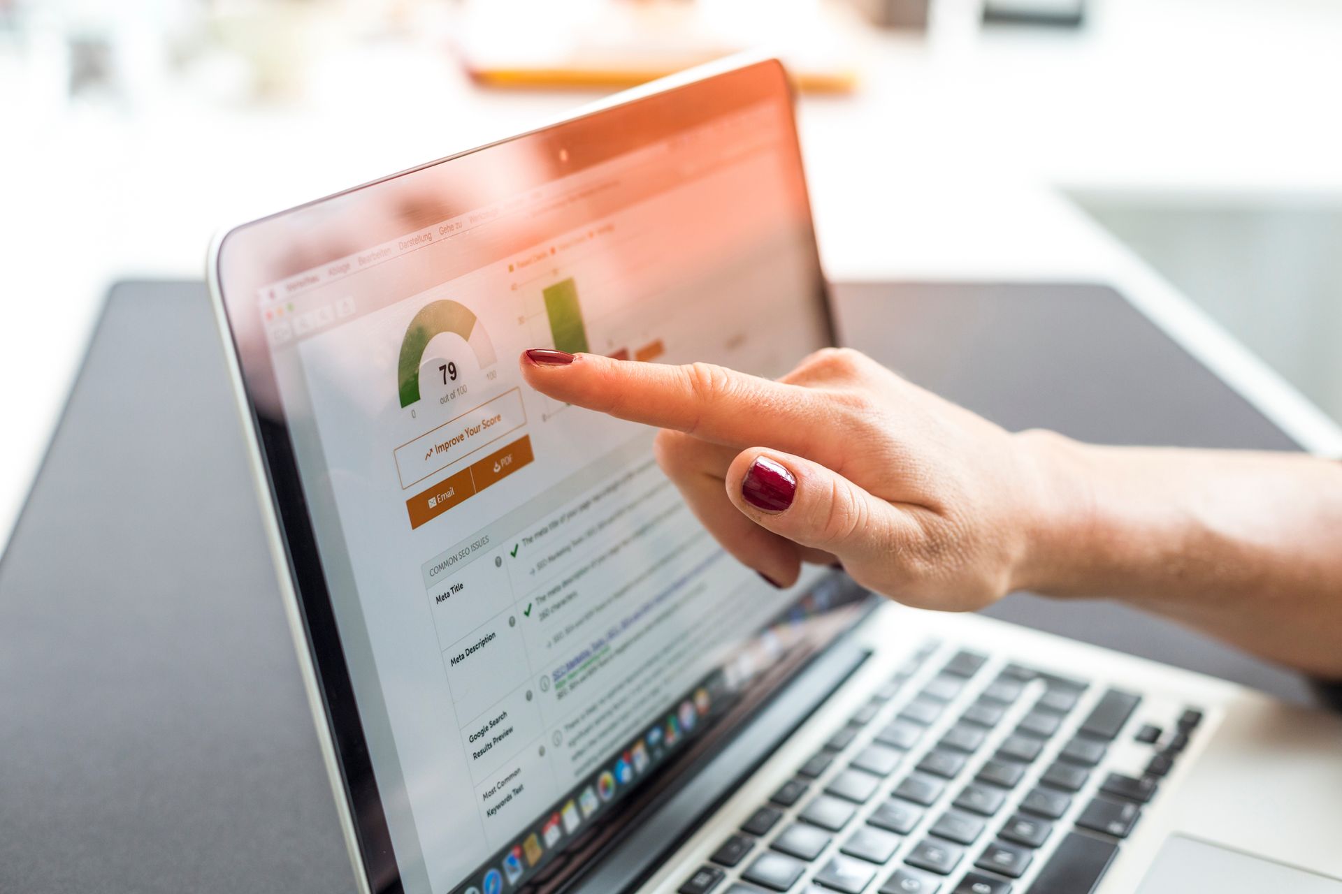 Hand pointing at a data chart on a laptop screen.