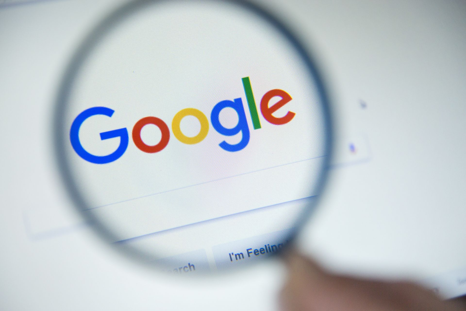 Magnifying glass over Google logo on a white screen.