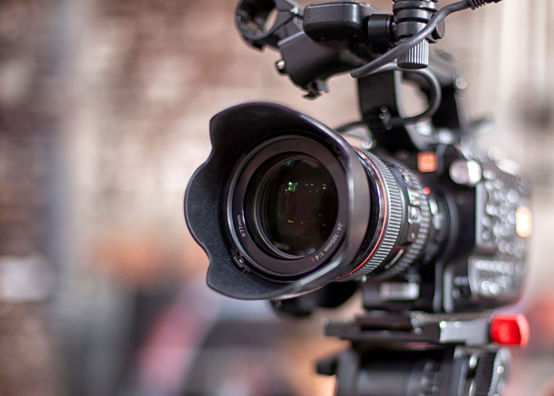 Professional video camera with large lens on a tripod, set up indoors