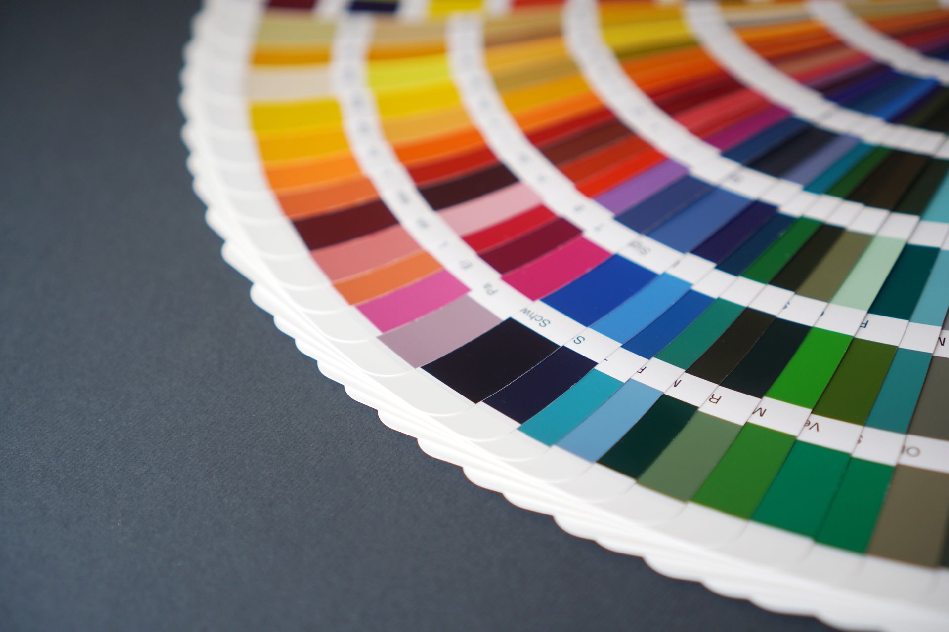 A fan deck of color swatches in various shades arranged in a circular pattern on a dark gray background.
