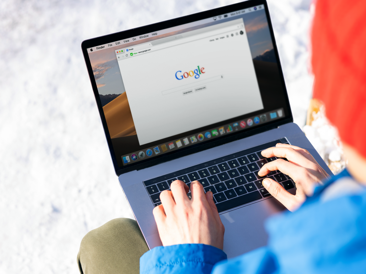 A person is typing on a laptop computer while sitting in the snow. A person is typing on a laptop computer while sitting in the snow.