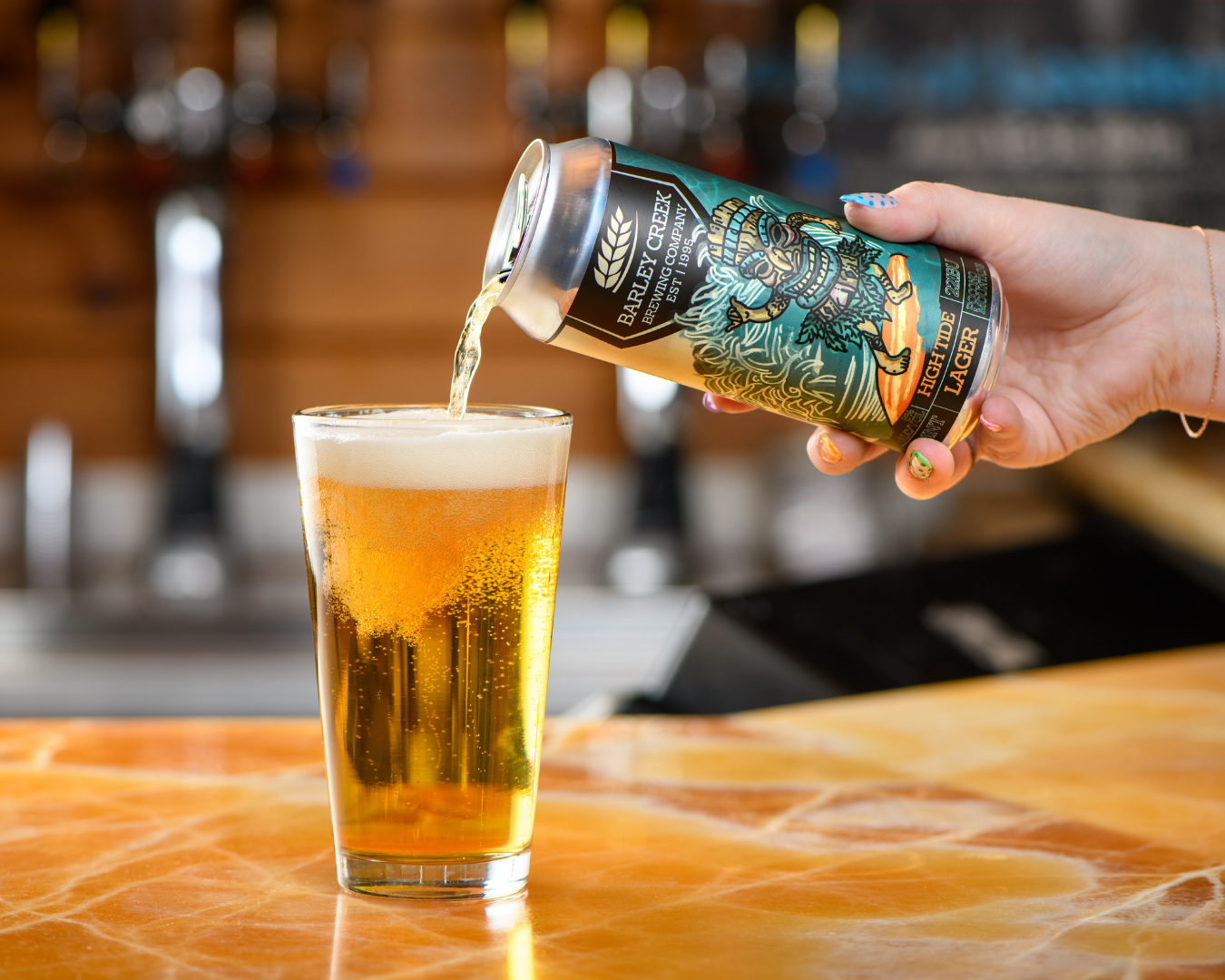 A person is pouring a can of beer into a glass.