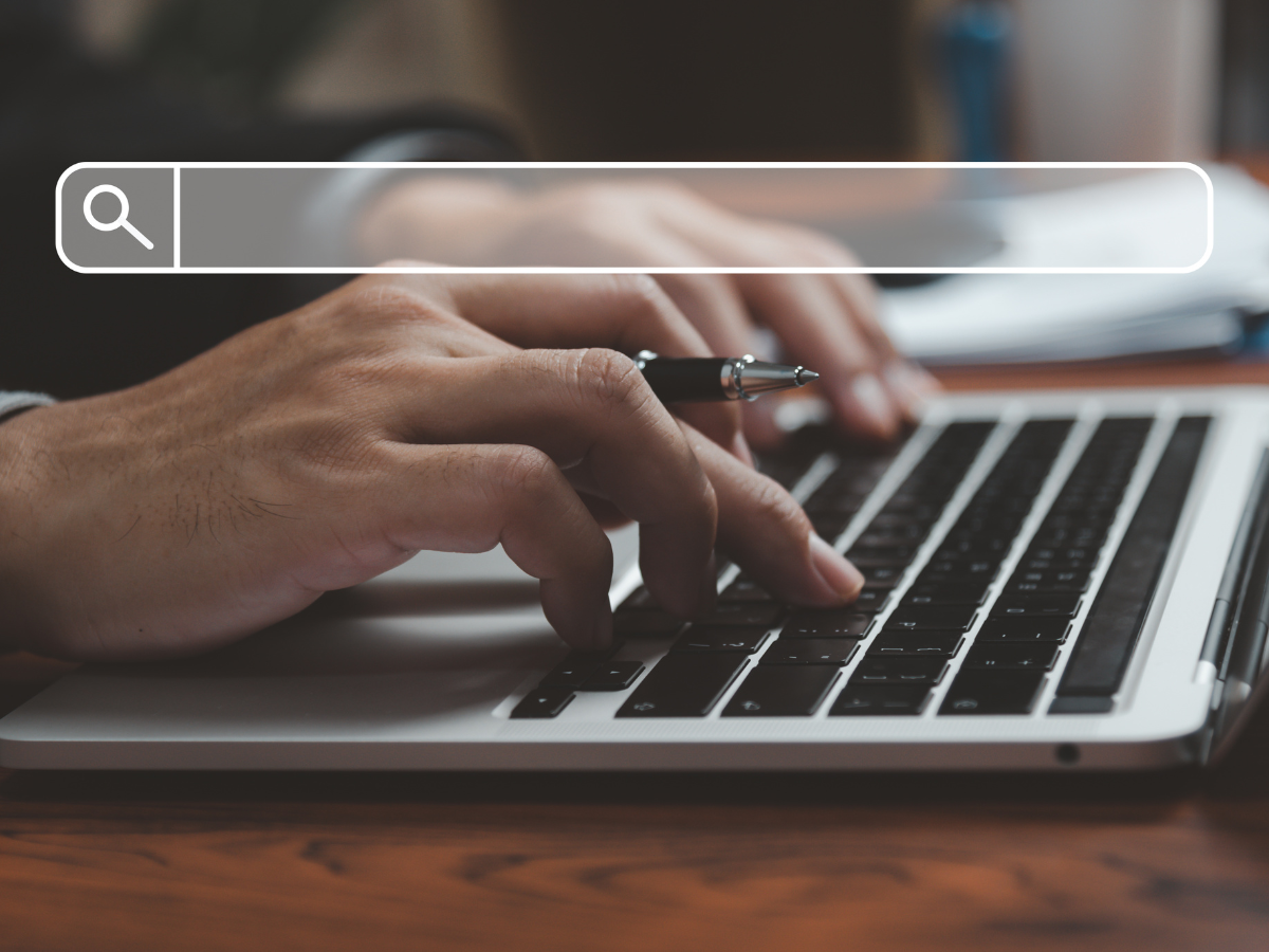 Person typing on laptop with search bar overlay.