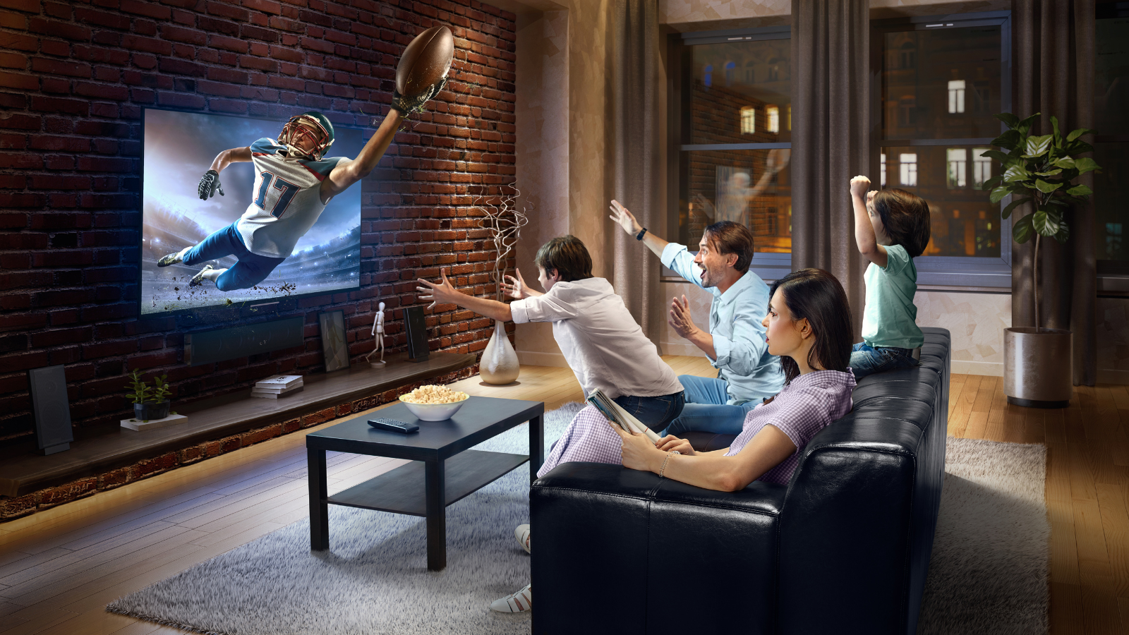 a family is sitting on a couch watching the Super Bowl on a television .