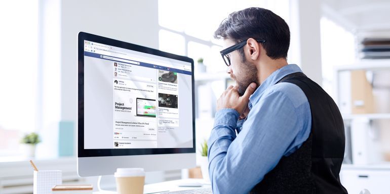 A man is sitting at a desk looking at a computer screen.