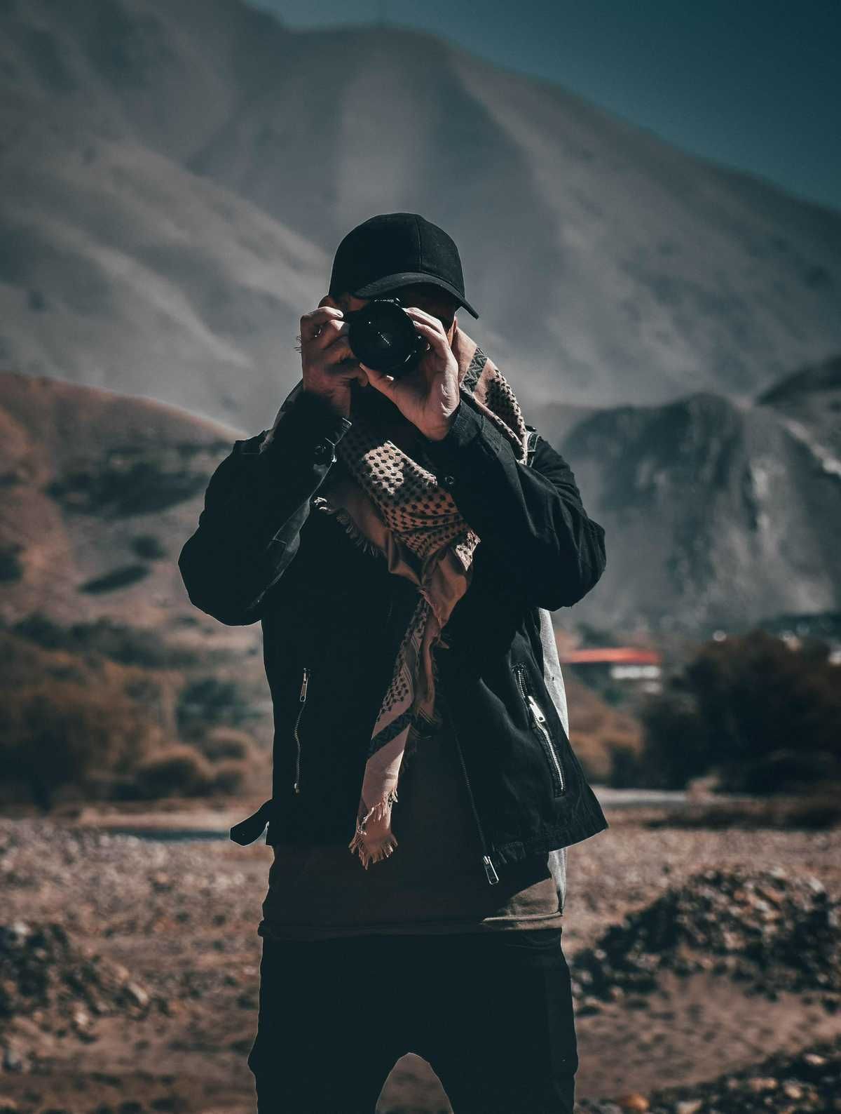 A man is taking a picture of a mountain with a camera.