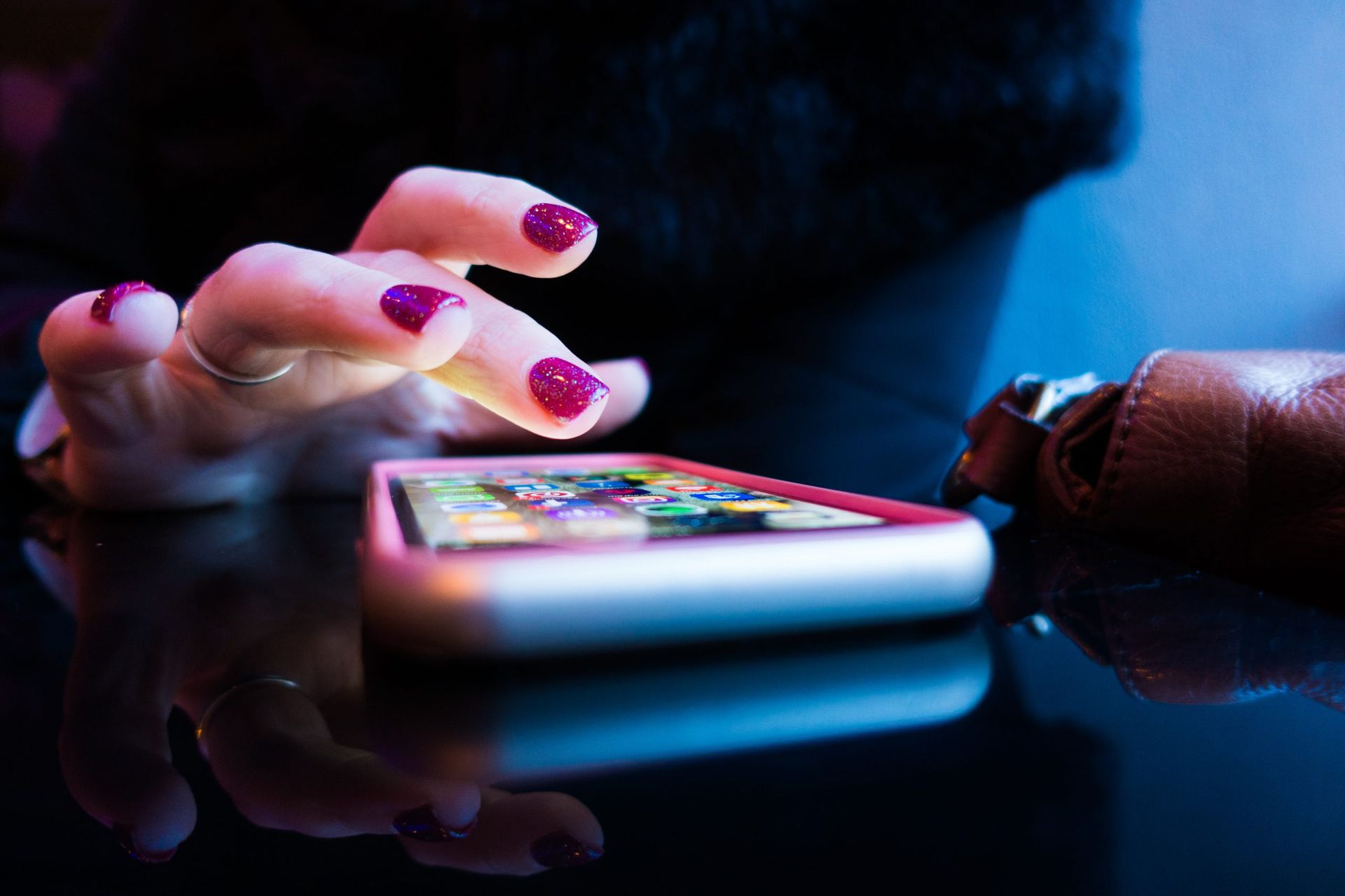 A woman with purple nails is using a cell phone.