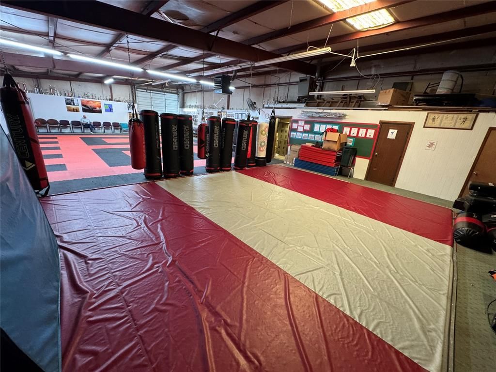 A boxing gym with a red, white and blue mat and boxing bags.