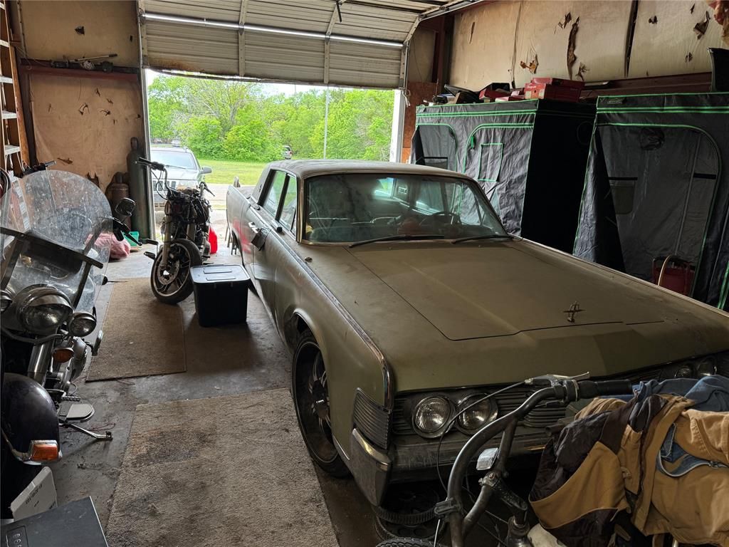 A car is parked in a garage next to a motorcycle.