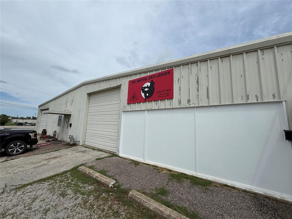 A white building with a red sign on it and a truck parked in front of it.