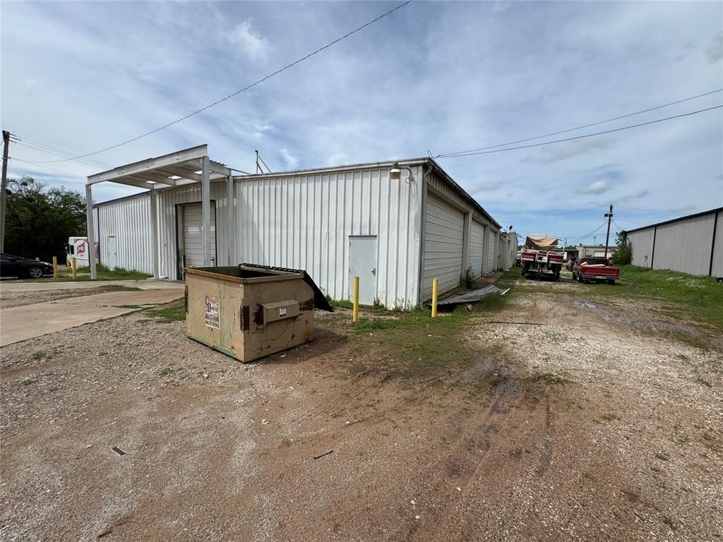 A large white building with a dumpster in front of it.