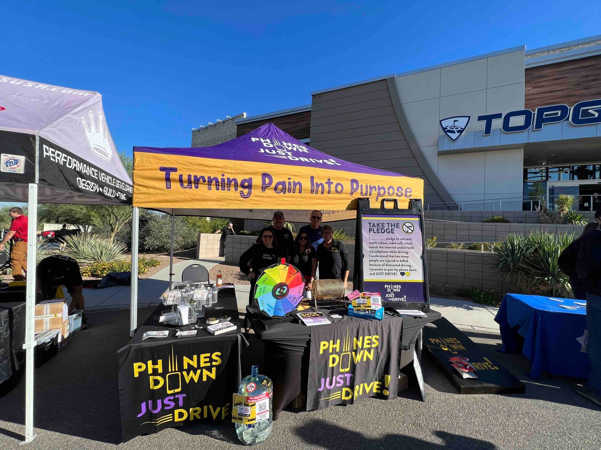 A group of people are standing under a tent that says turning pain into purpose.