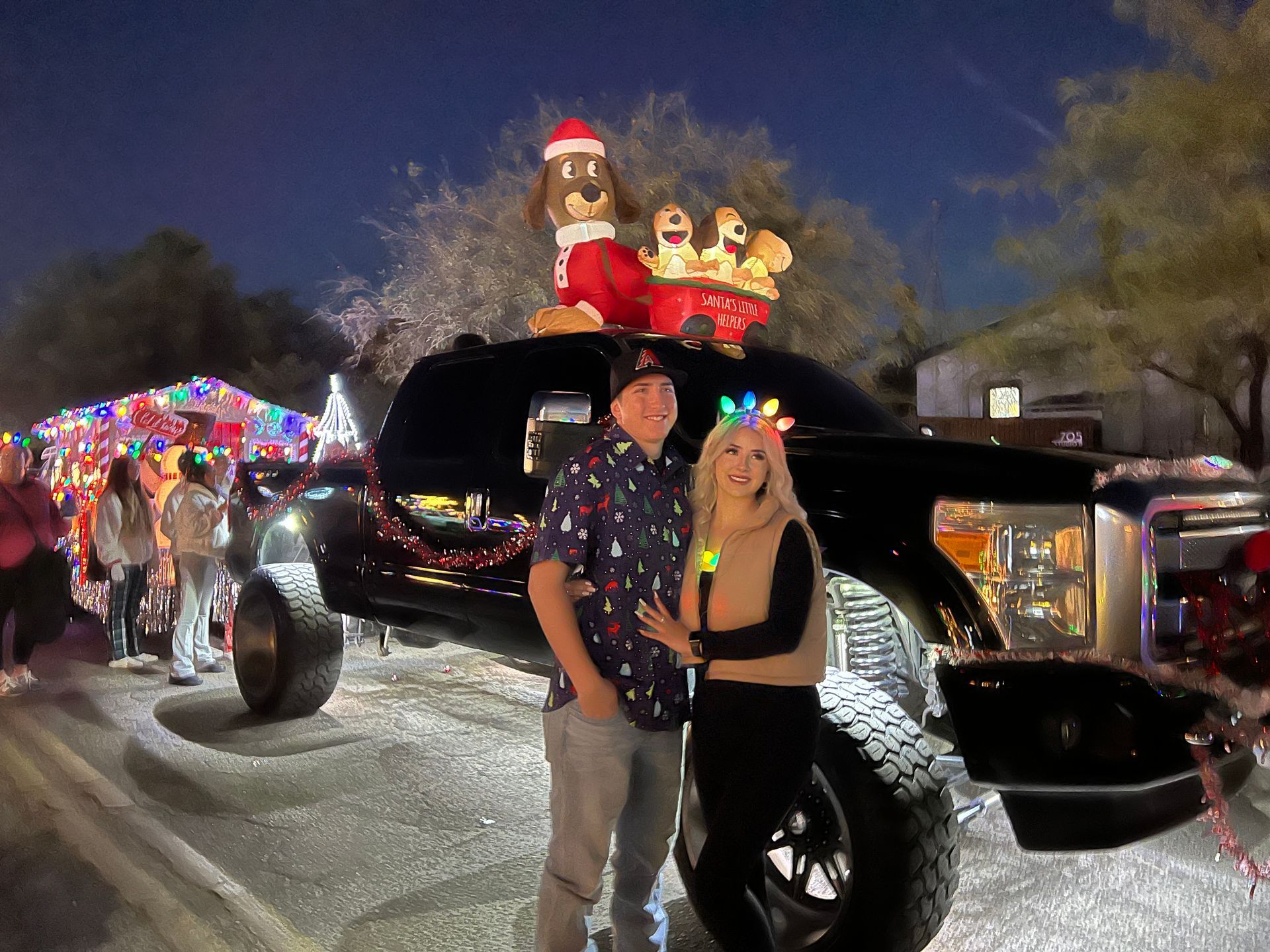 A man and a woman are standing in front of a truck decorated for christmas.