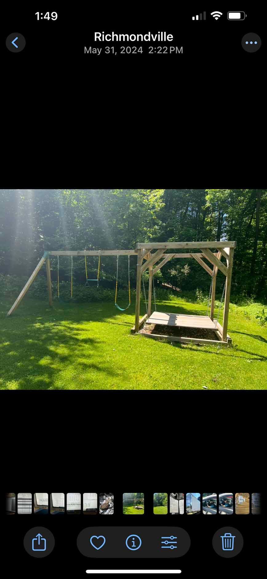A wooden playset and swing set in a grassy yard, with trees in the background.
