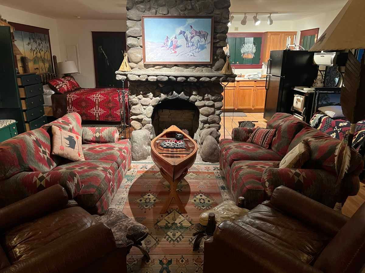Cozy living room with stone fireplace, sofas, canoe decor, and Southwestern patterned rugs.