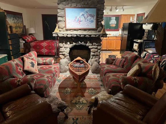 Cozy living room with stone fireplace, sofas, canoe decor, and Southwestern patterned rugs.