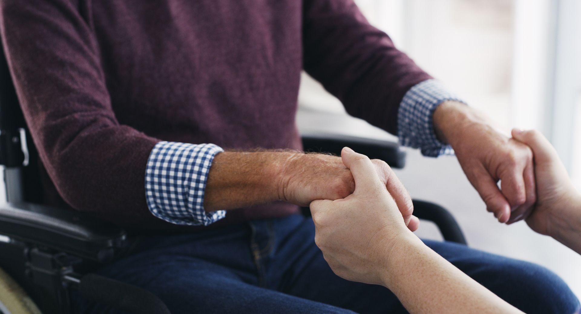 Person in wheelchair holding hands with another person.