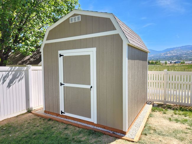 White garage with brown trim, door, and closed garage door on a concrete pad with grass.