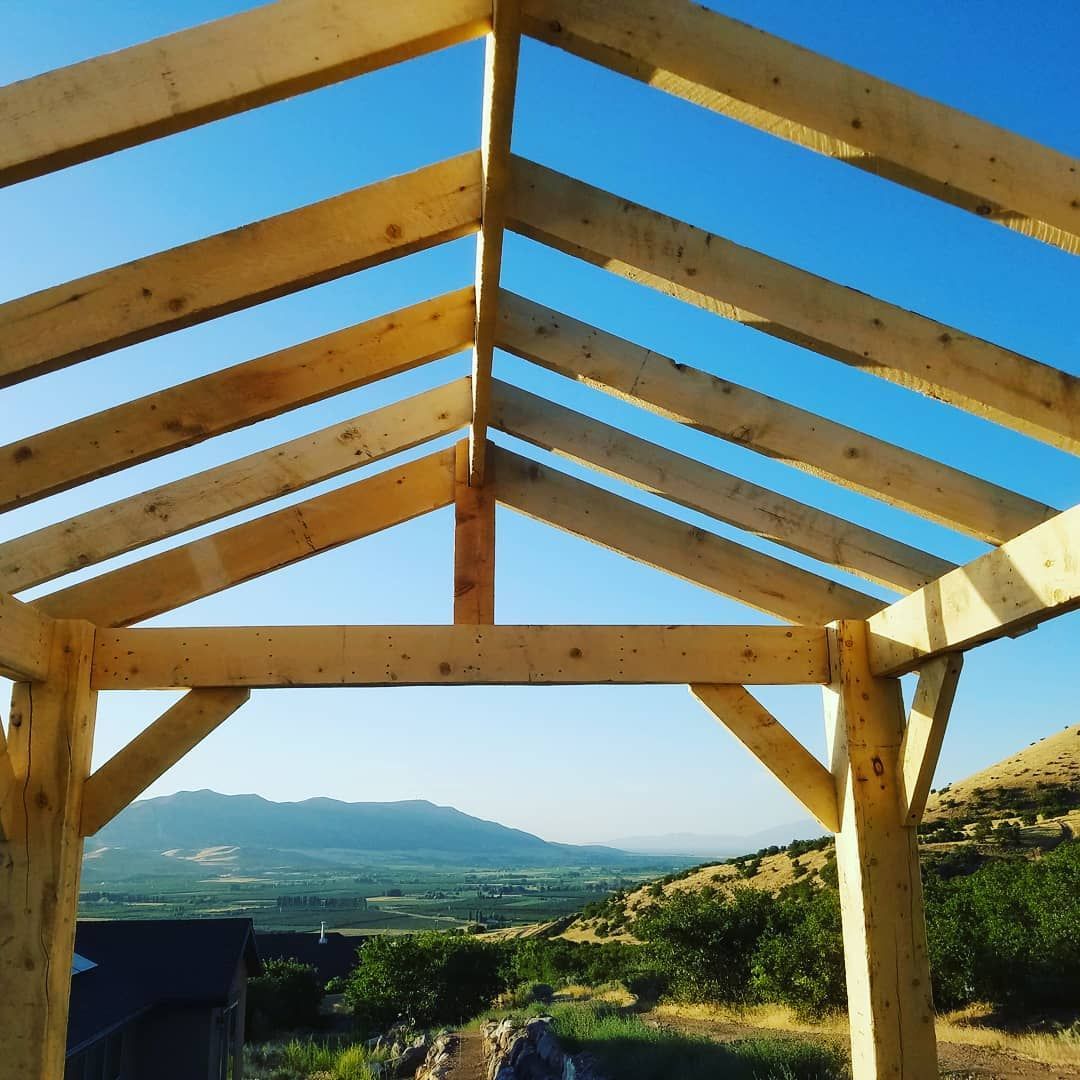 Wooden frame of a building under construction, against a mountain backdrop.