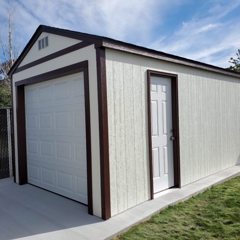 Off-white storage shed with a brown trim, featuring a white garage-style door and a single side entry door on a concrete pad.