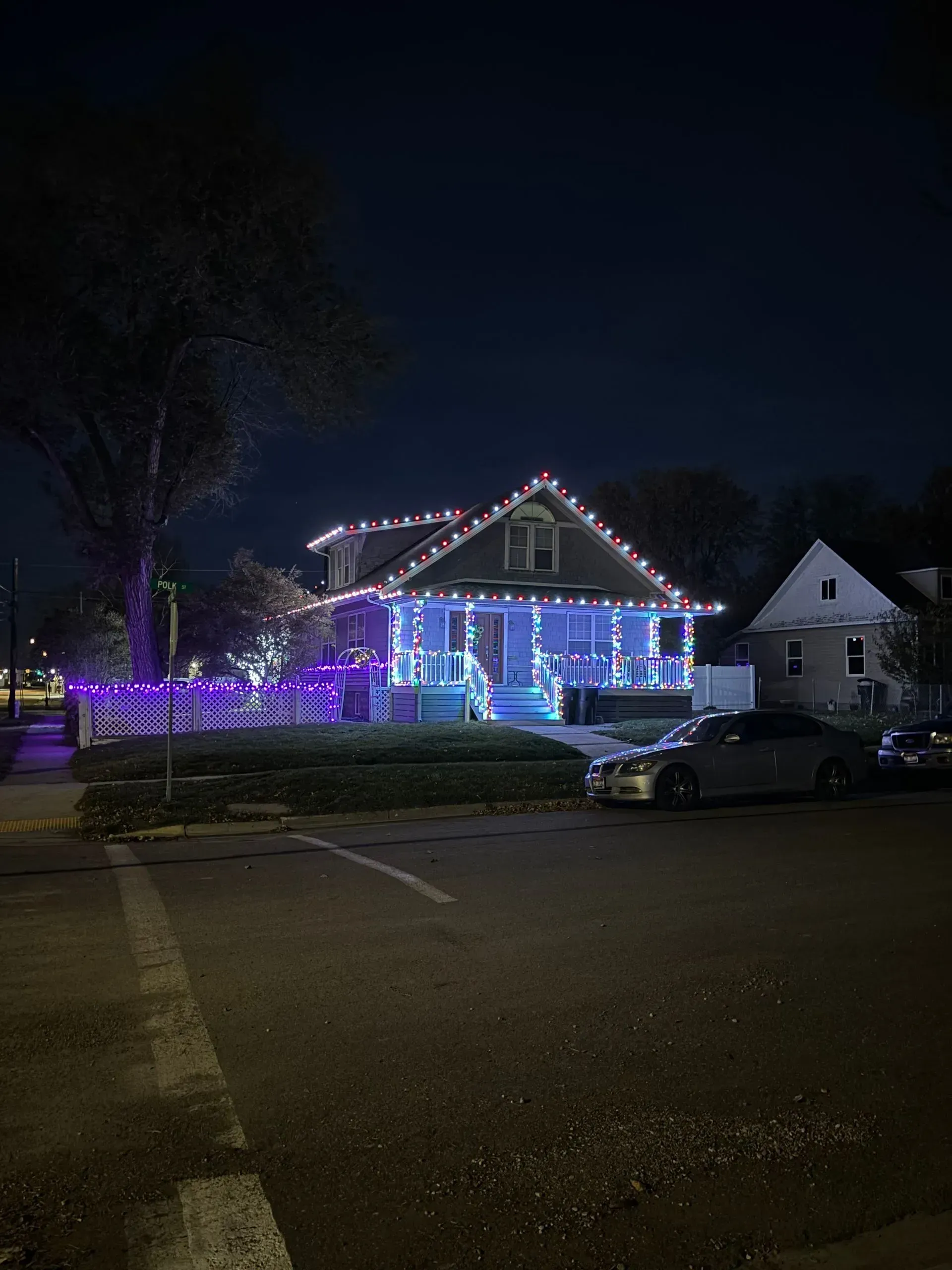 A house decorated with christmas lights is lit up at night.