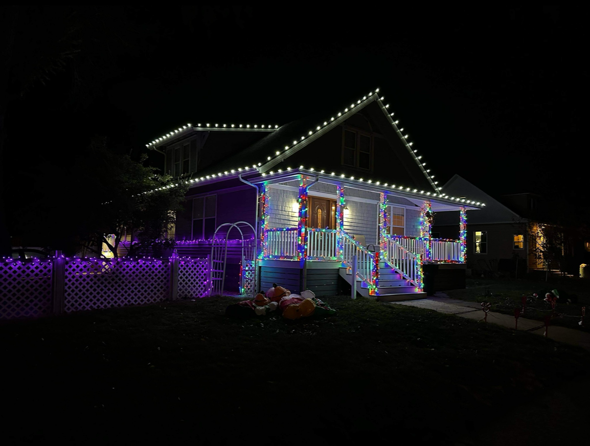 House decorated with colorful lights for a nighttime celebration, including purple, blue, and white.
