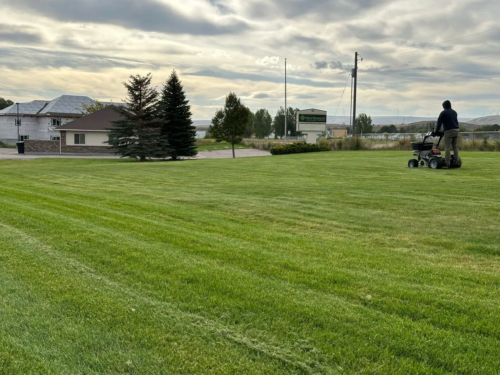 A man is mowing a lush green field with a lawn mower.