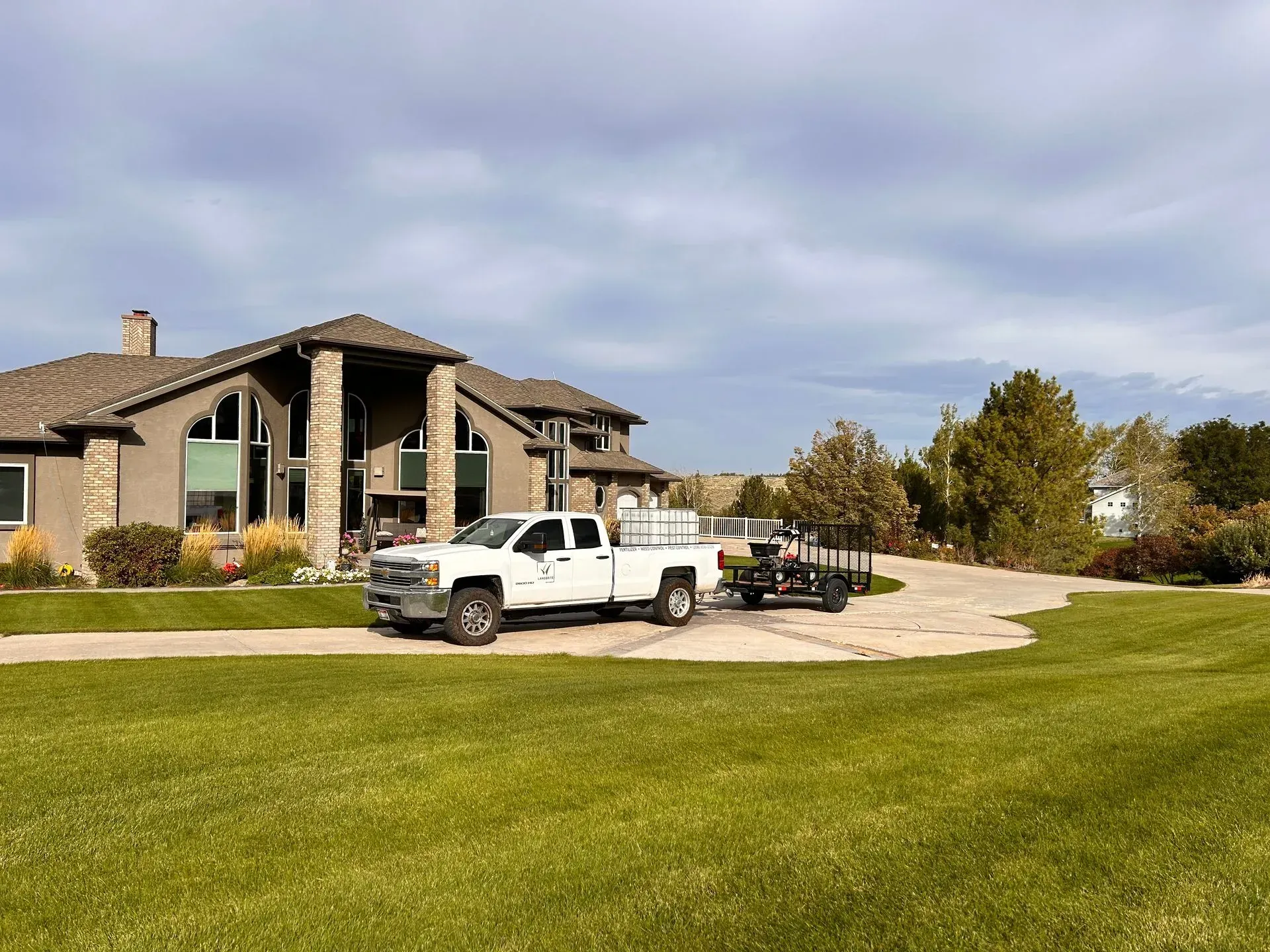 A white truck is parked in front of a large house.