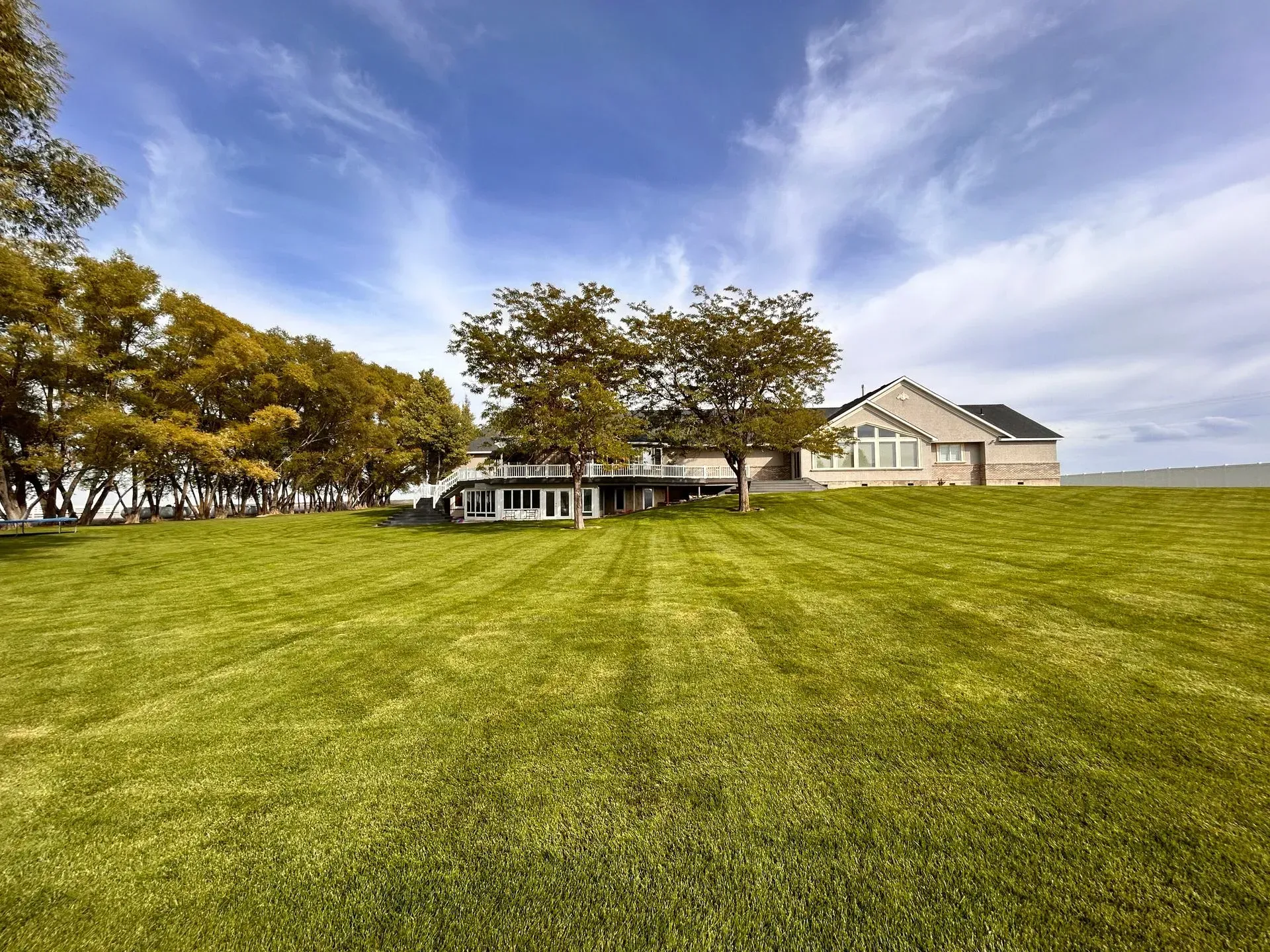 A house is sitting on top of a lush green hill surrounded by trees.