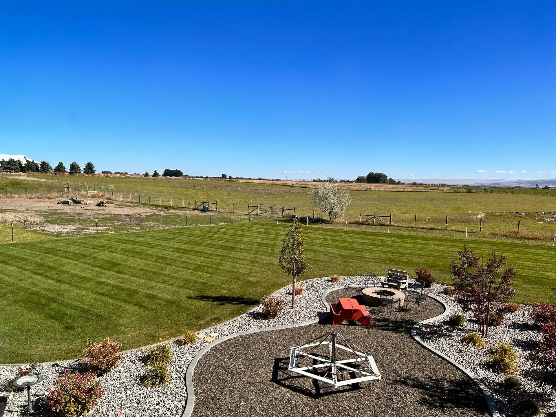 There is a fire pit in the middle of a lush green field.