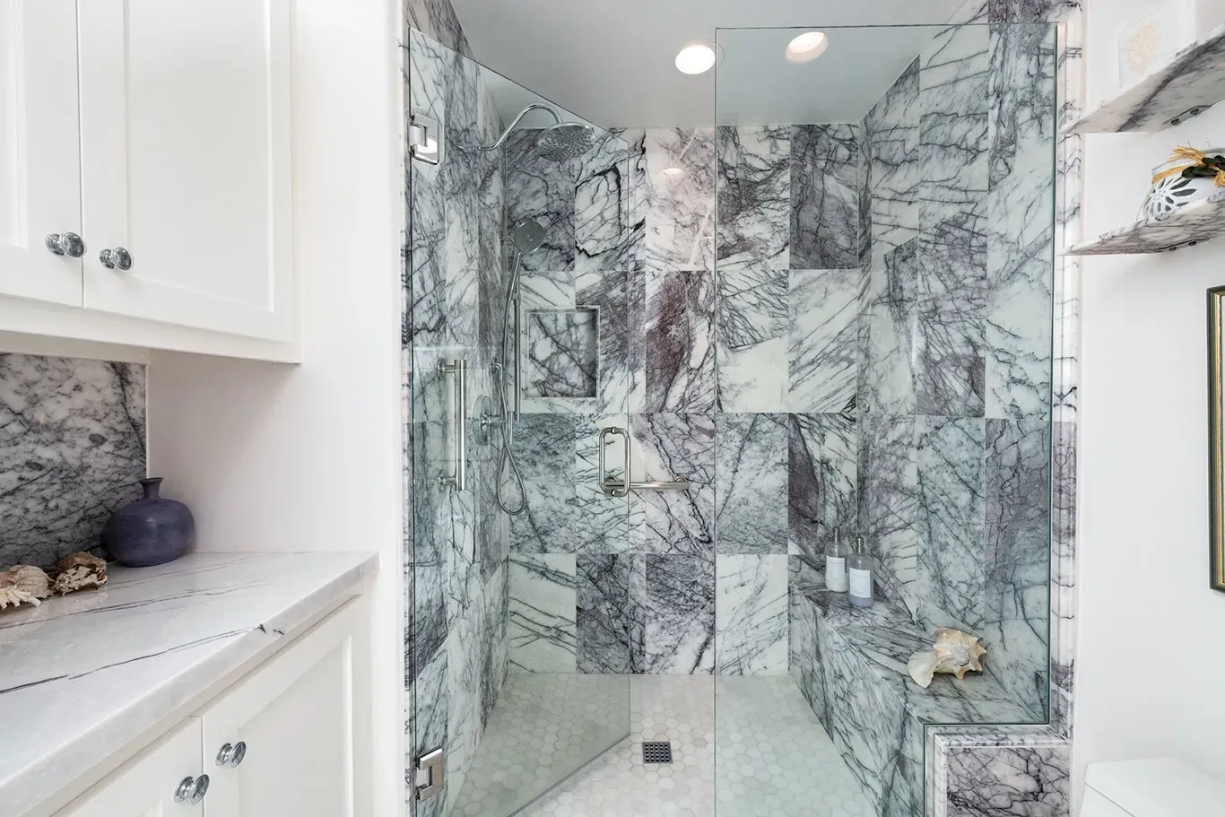A bathroom with marble tiles and a walk in shower.