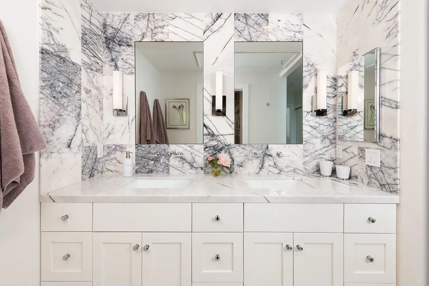 A bathroom with two sinks , a mirror and a marble wall.