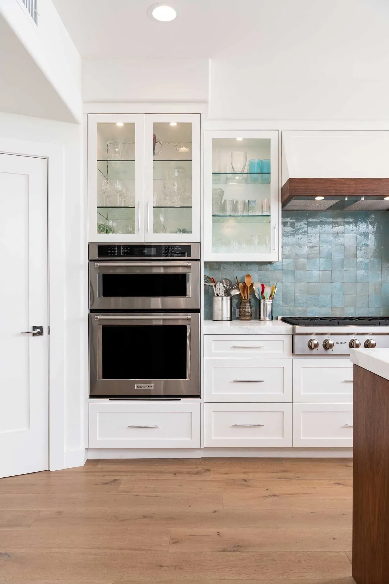A kitchen with white cabinets , stainless steel appliances , and wooden floors.