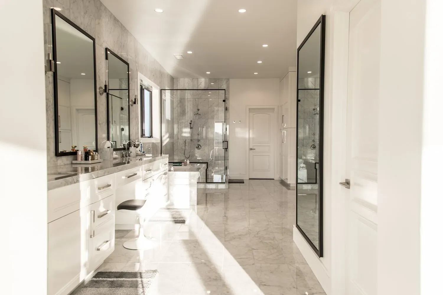 A bathroom with two sinks , two mirrors and a walk in shower.