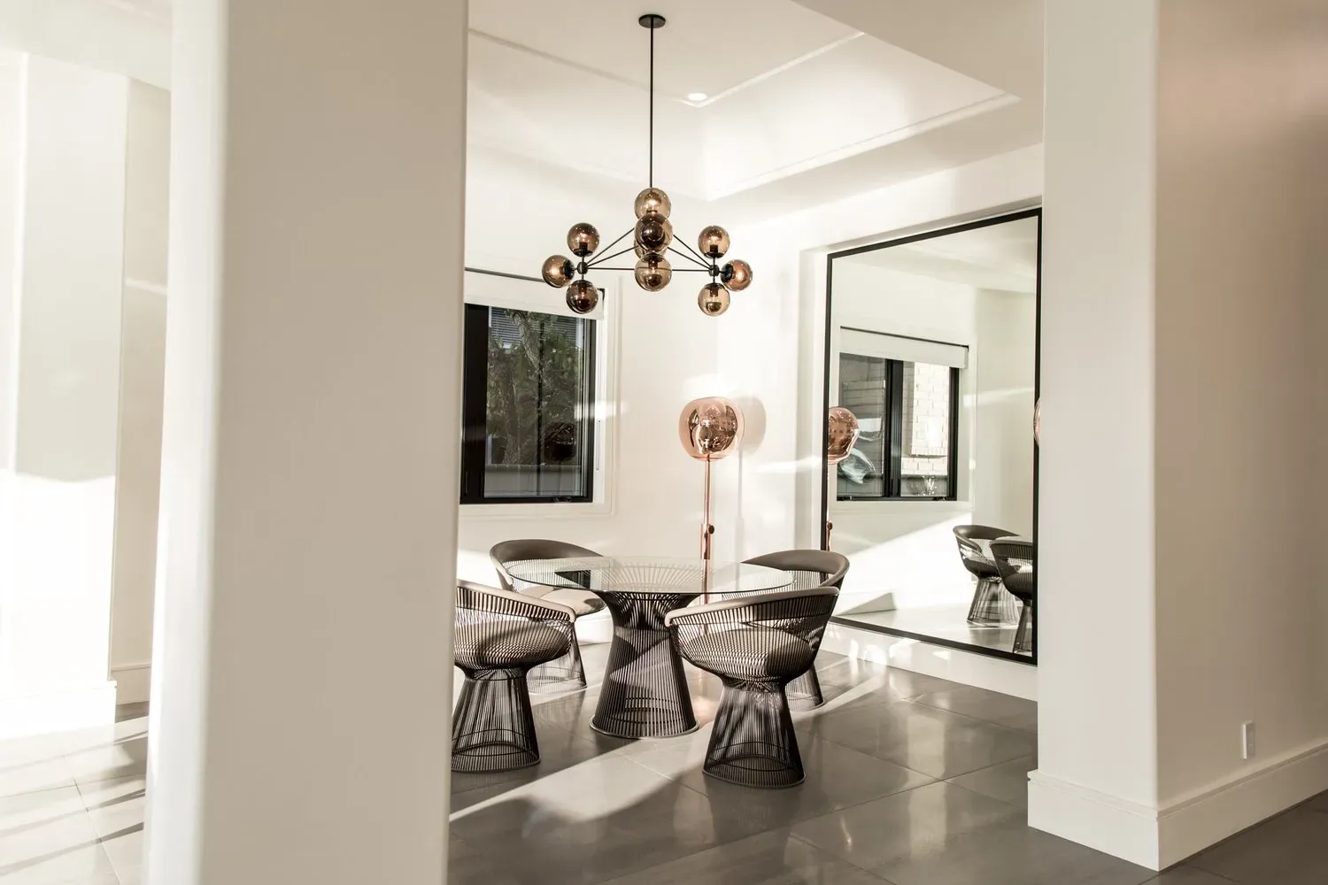 A dining room with a table and chairs and a large mirror.