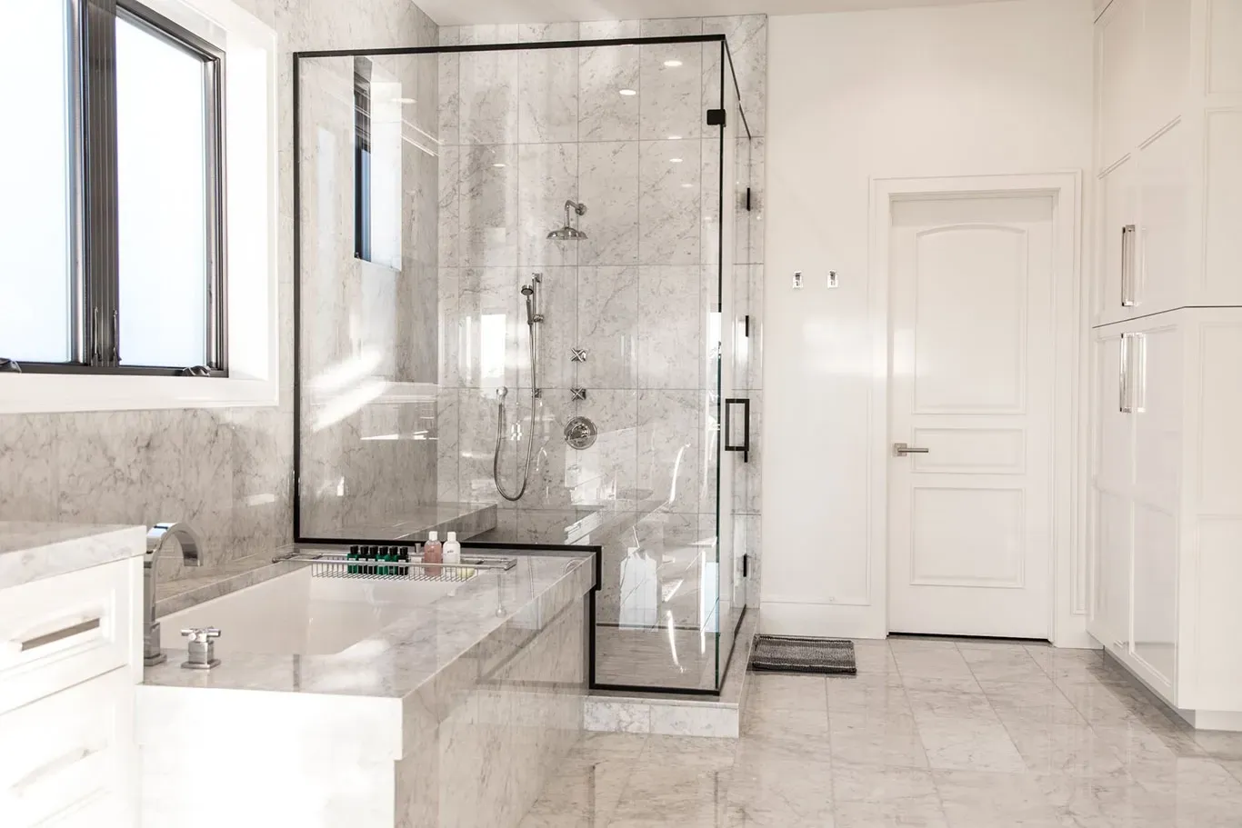 A bathroom with a walk in shower , tub , sink and window.