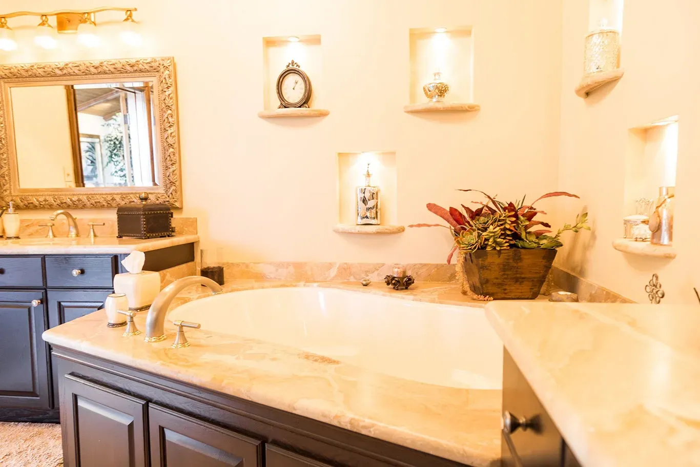 A bathroom with two sinks , a tub , a mirror and a clock on the wall.