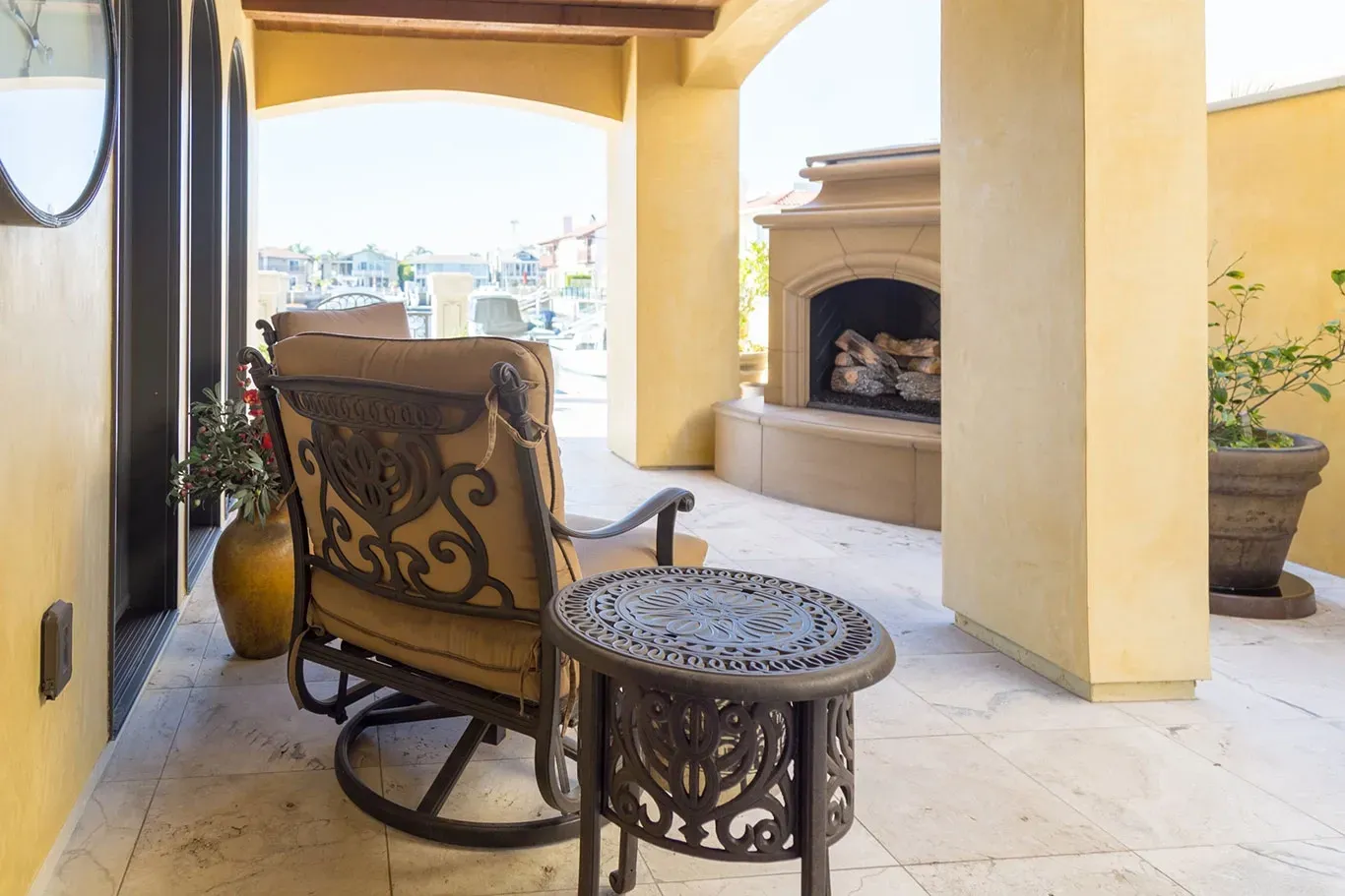 A patio with a rocking chair , table and fireplace.