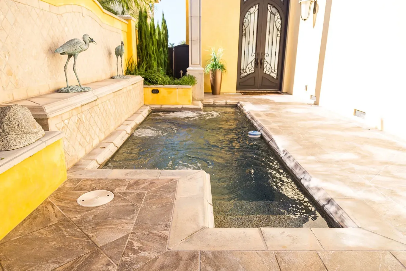 A small swimming pool with a statue of a flamingo on the side of it.