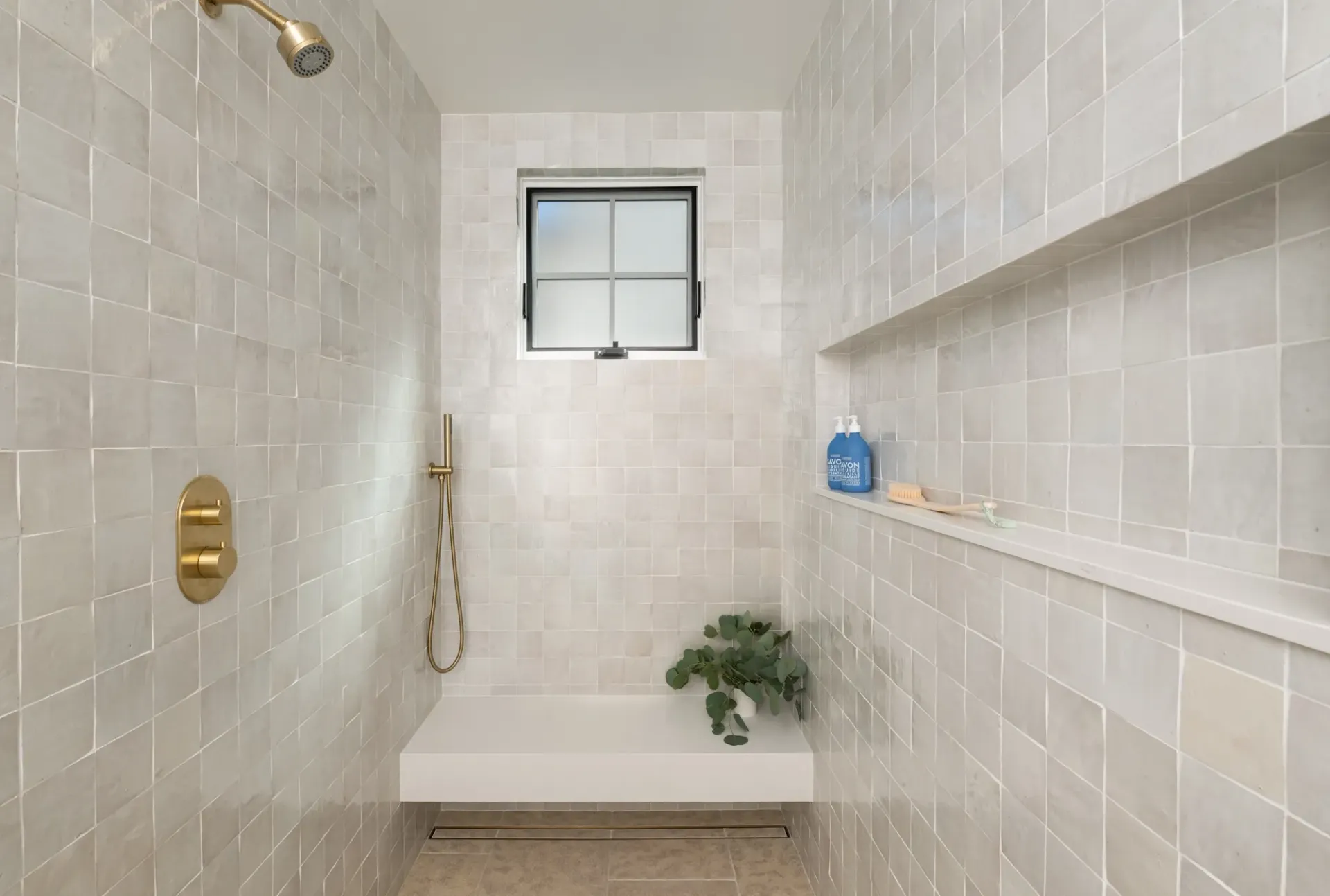A bathroom with a walk in shower and a window.