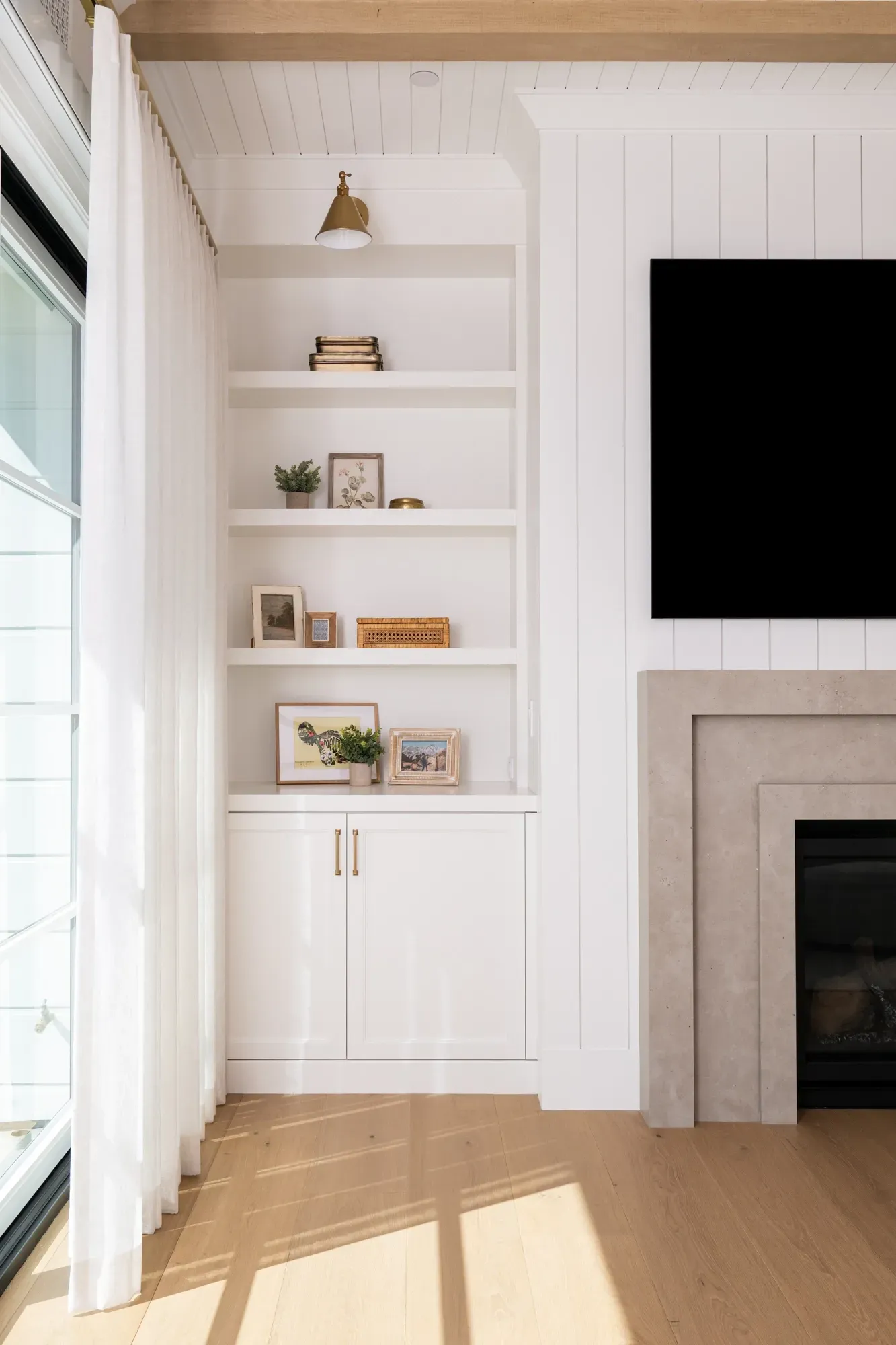 A living room with a fireplace , built in shelves , and a flat screen tv.