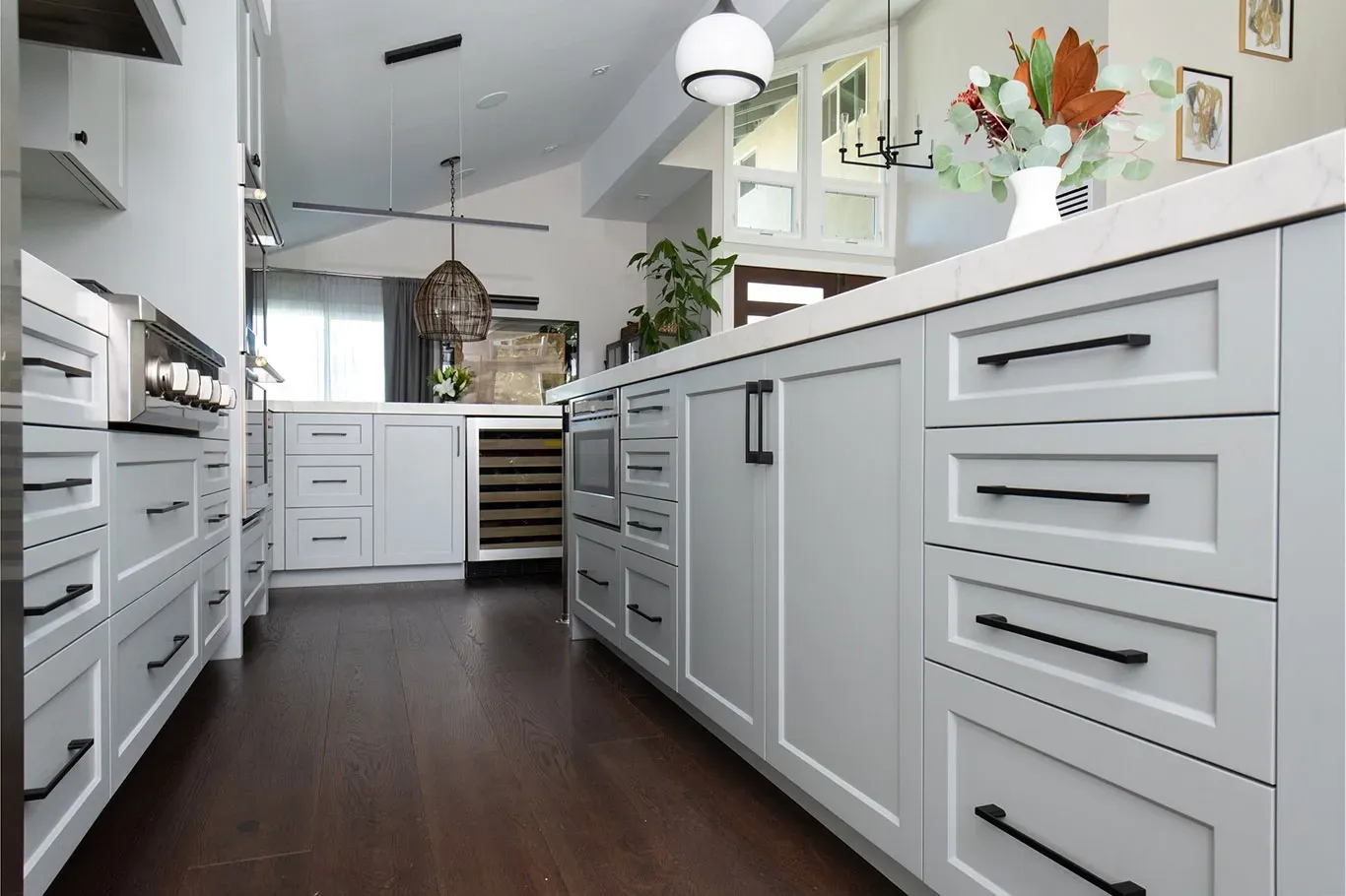 A kitchen with white cabinets and black handles