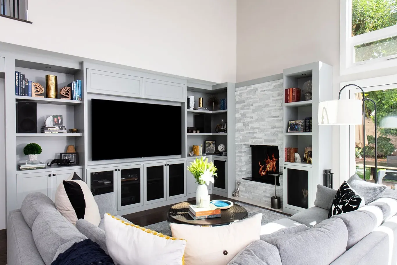 A living room with a couch , television , fireplace and shelves.