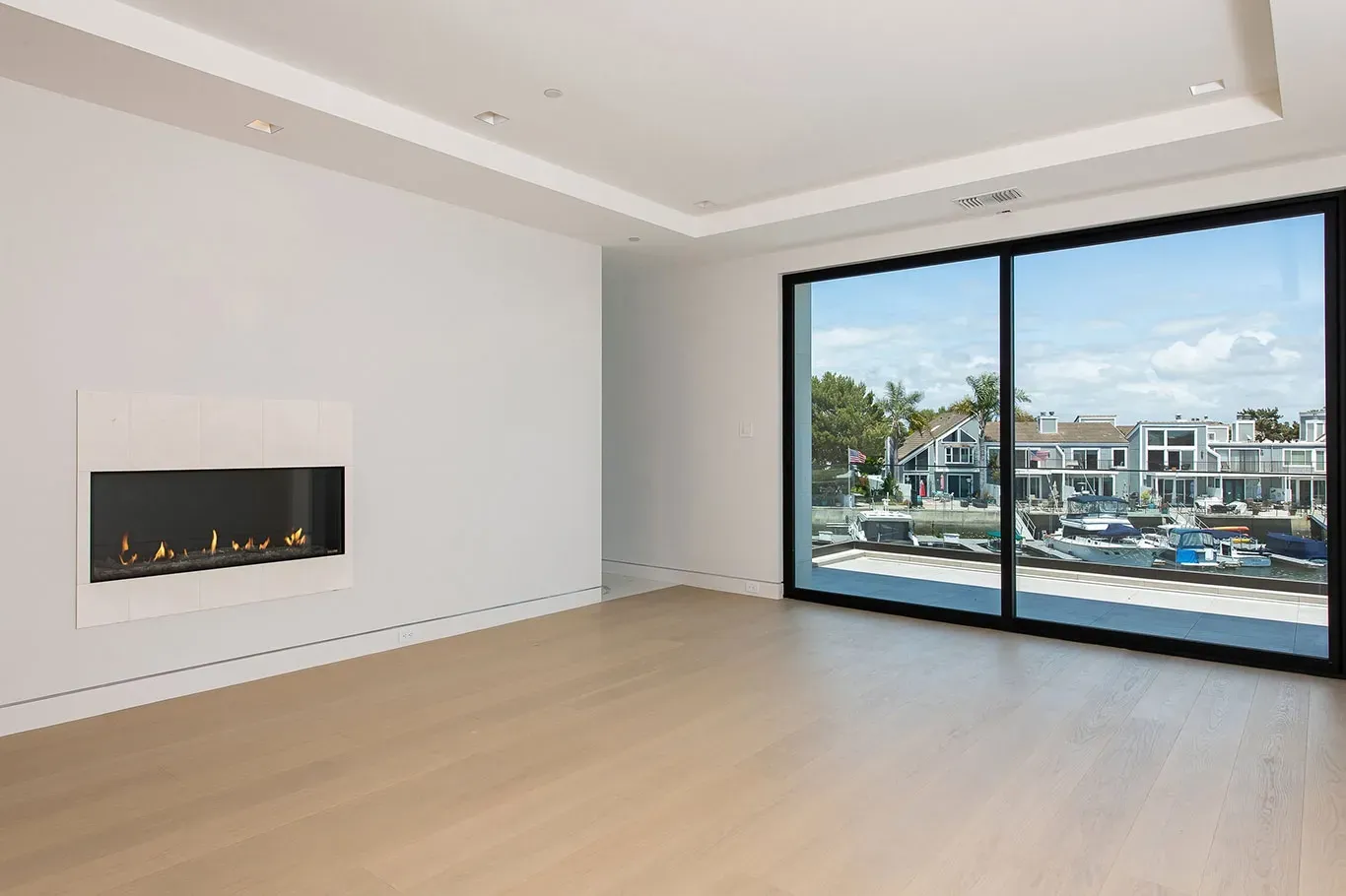 An empty living room with a fireplace and sliding glass doors.